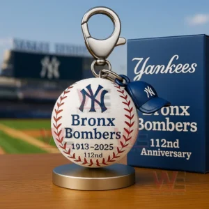 Yankees baseball keychain with NY logo Bronx Bombers text 1913 to 2025 112nd and a blue anniversary box on a table with a stadium background.