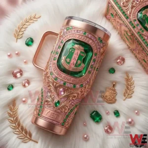 Rose gold Alpha Kappa Alpha tumbler displayed on white fur with green and pink jewel decorations!