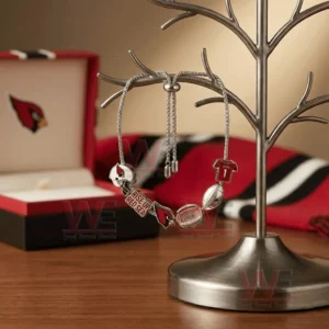 Silver adjustable charm bracelet with Arizona Cardinals helmet logo stadium football and jersey charms hanging on a jewelry stand with team themed background.