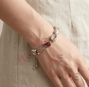 Hand wearing a silver adjustable charm bracelet with Arizona Cardinals helmet logo stadium and Rise Up Red Sea message charms.