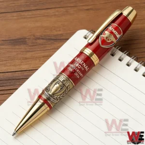 Red and gold Arsenal anniversary ballpoint pen displayed on a notebook with detailed crest and metallic finish!