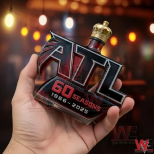 A hand holding a Crown Royal whisky bottle shaped like the Atlanta Falcons logo celebrating sixty seasons with red glass details and a gold crown stopper!