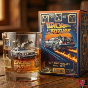 A collectible whiskey glass with a Back To The Future inspired car graphic and anniversary marking standing on a wooden surface next to a themed display box!