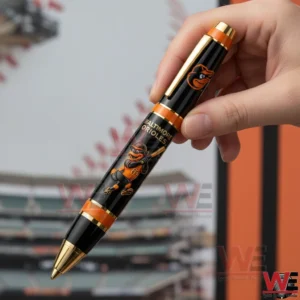 Baltimore Orioles 125th Anniversary Limited Edition 1901-2026 Pen 3 Hand holding a Baltimore Orioles themed commemorative pen with mascot artwork and a baseball stadium in the background!