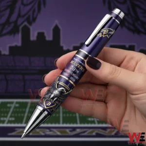 Baltimore Ravens 30th Anniversary 1996-2026 Pen 3 Hand holding a purple Baltimore Ravens thirtieth anniversary ballpoint pen with logo and raven artwork in front of a football field backdrop.