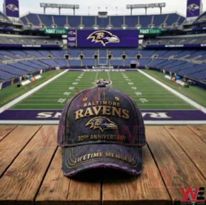 A Baltimore Ravens anniversary cap resting on a wooden table with a football stadium and green field visible in the background!