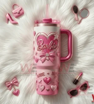 Pink Barbie tumbler with handle and straw featuring heart and bow decorations placed on a white fur background with pink accessories!