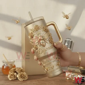 Hand holding a gold embossed handled tumbler with queen bee and floral relief in a warm studio setting with decorative props!