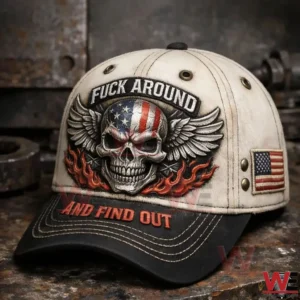 Close up of a beige and black baseball cap with a skull wings flames graphic and an American flag patch on the side.