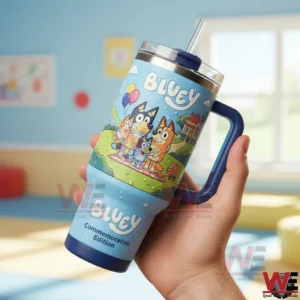 Hand holding a Bluey commemorative edition tumbler with colorful family artwork a straw lid and a bright softly lit interior background!