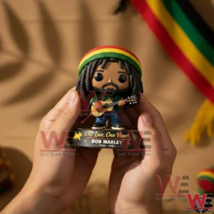 Close up of hands holding a Bob Marley inspired pop style figure with dreadlocks and red yellow green cap holding a guitar on a one love themed base!