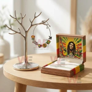 Silver adjustable charm bracelet with reggae themed guitar music peace palm tree and flag charms hanging on a jewelry stand next to a Bob Marley themed box.