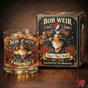 A memorial whiskey glass with ice and a matching collector gift box featuring a Bob Weir tribute design with roses portrait artwork and the years 1947 2026 on a dark background