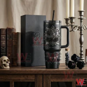 A Bring Me The Horizon insulated tumbler displayed on a wooden table with gothic style decor and books!
