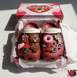 Red Buc Ees clogs in an open pink gift box with heart themed branding and multiple Valentine charms like a beaver face donut chocolate roses and love letter on the shoes!