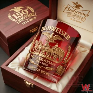 A decorative Budweiser anniversary glass resting on soft fabric inside an open wooden case with rich red tones!