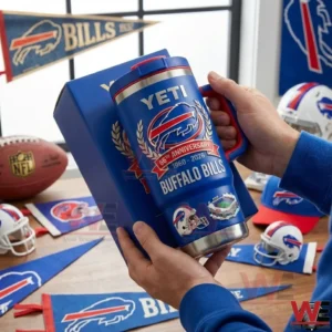 Hands holding a blue Buffalo Bills anniversary insulated travel mug with handle beside a matching box with team flags football helmets and memorabilia on a table!