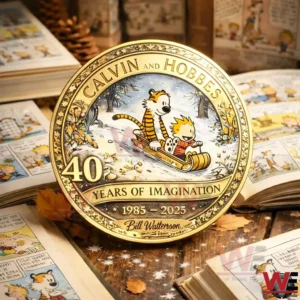 Gold anniversary coin with Calvin and Hobbes sledding in snow framed by ornate border and forty years of imagination text on a cozy tabletop with comic book pages in the background!