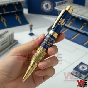 Hand holding a blue and gold Chelsea FC commemorative pen with a small stadium model in the background!