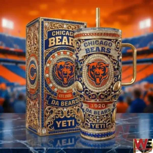 A detailed Chicago Bears tumbler with rich ornamental patterns and team branding stands next to its matching box on a reflective surface inside a football arena!