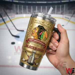 A single hand displays a gold toned hockey tumbler with detailed graphics against a bright ice rink setting!