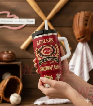 Hands holding a red Cincinnati Reds Redlegs tumbler with white handle and straw showing 145th anniversary 1881 2026 logo in a baseball memorabilia room