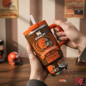 Hands holding a brown Cleveland Browns anniversary insulated travel mug with orange lid handle and straw in a room with team posters and memorabilia!