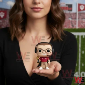 A miniature Indiana Hoosiers coach figure with glasses headset and trophy stands on a hand with a football field in the background!