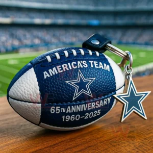 Blue and white Dallas Cowboys football keychain with star logo Americas Team text 65th anniversary 1960 2025 and a star charm on a wooden table with a stadium background!