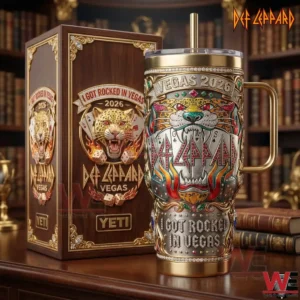 An upright Def Leppard Vegas 2026 tumbler with gold accents and casino themed artwork standing beside an elegant collector style box in a warm library environment!