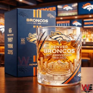 A Denver Broncos anniversary whisky glass with detailed team emblem and stadium design placed beside a branded presentation box on a bar surface!