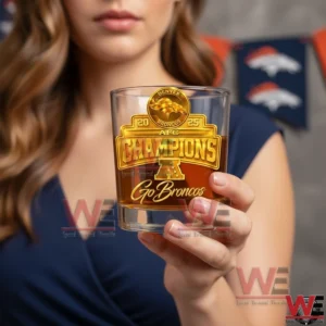 A woman holds a clear whiskey glass filled with amber liquid displaying a gold Denver Broncos AFC Champions emblem and Go Broncos text against a softly blurred sports themed background!