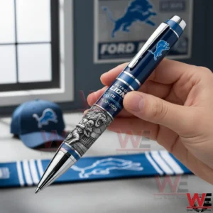 Detroit Lions 96th Anniversary 1930-2026 Pen 3 Hand holding a Detroit Lions anniversary pen with navy barrel silver trim light blue accents and engraved lion detailing.