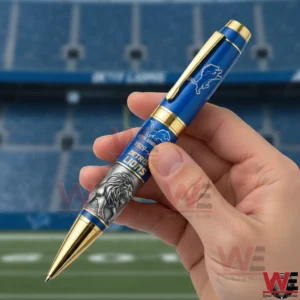Hand holding a blue and gold Detroit Lions anniversary pen with 97th Anniversary 1929 2026 text in front of a football stadium background.