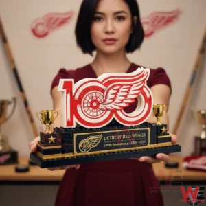 A person holding a Detroit Red Wings 100th anniversary brick display with the winged wheel logo!