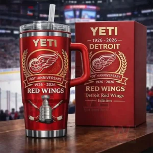 A red Detroit Red Wings 100th anniversary insulated tumbler with handle lid and straw beside a matching red gift box shown in front of a blurred hockey arena backdrop!
