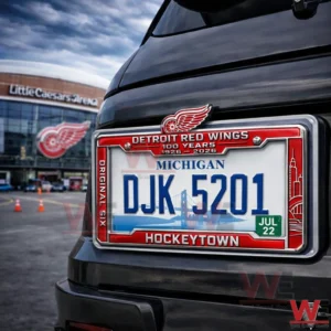 Rear of a vehicle displaying a Michigan license plate DJK five two zero one in a Detroit Red Wings themed frame with the text Hockeytown and the arena in the background.