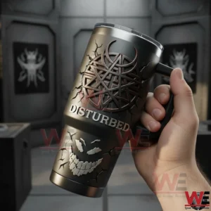 Hand holding a Disturbed insulated tumbler with handle dark metallic emblem and bold Disturbed text with an industrial blurred background!