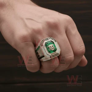 A hand wearing a large gold and silver championship ring with a green gemstone face and a skull in a green cap surrounded by sparkling stones and Dropkick Murphys text.