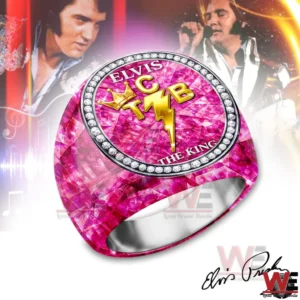 A pink faceted gemstone style ring with an oval face showing ELVIS and THE KING text plus a gold TCB crown and lightning bolt emblem surrounded by diamond like stones with faded singer performance images in the background!