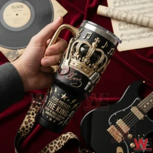 Hand holding a black handled tumbler with gold crown musical notes and rock themed embossed details on red fabric with vinyl record sheet music and guitar props!