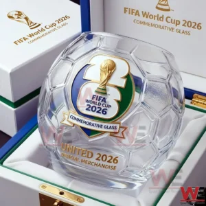 A transparent soccer ball inspired whiskey glass with World Cup 2026 branding resting inside an official commemorative display case!
