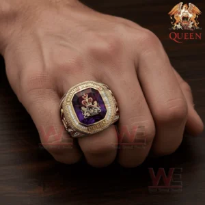 Hand wearing a large gold and silver ring with a purple gemstone and Queen crest design.