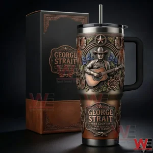 Handled tumbler with embossed cowboy playing guitar and western floral details beside a George Strait gift box on a dark studio background!