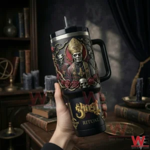 Hand holding a black gothic handled tumbler with skull and robed figure design in a dark study setting!