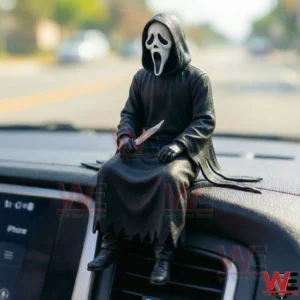Small Ghostface style figure in a black hooded robe and white mask sitting on a car dashboard while holding a knife.