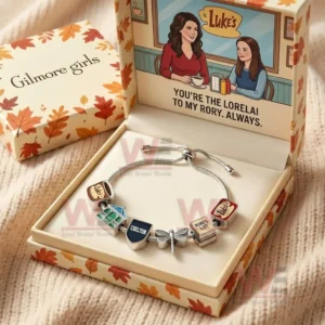 Open autumn themed gift box holding a silver adjustable charm bracelet with Gilmore Girls charms and a lid illustration with a friendship message.