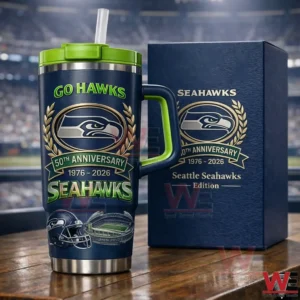 Dark blue and green Seattle Seahawks fiftieth anniversary insulated tumbler with handle and straw beside a matching collector edition box with a blurred stadium background!