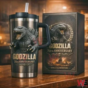 Dark stainless Godzilla 70th anniversary tumbler with handle and straw next to a matching collector style gift box featuring Godzilla in a laurel wreath and King of the Monsters text