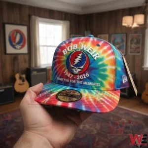 Hand holding a vibrant tie dye cap with skull emblem in front of a music themed interior with guitars and wall art!